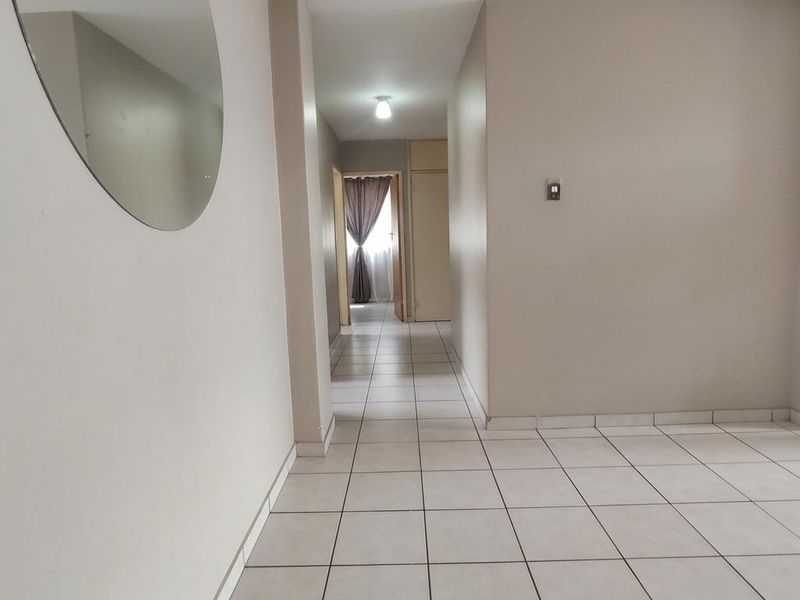A clean and neutral hallway featuring light-colored floor tiles, providing a bright and functional transition space within the apartment.