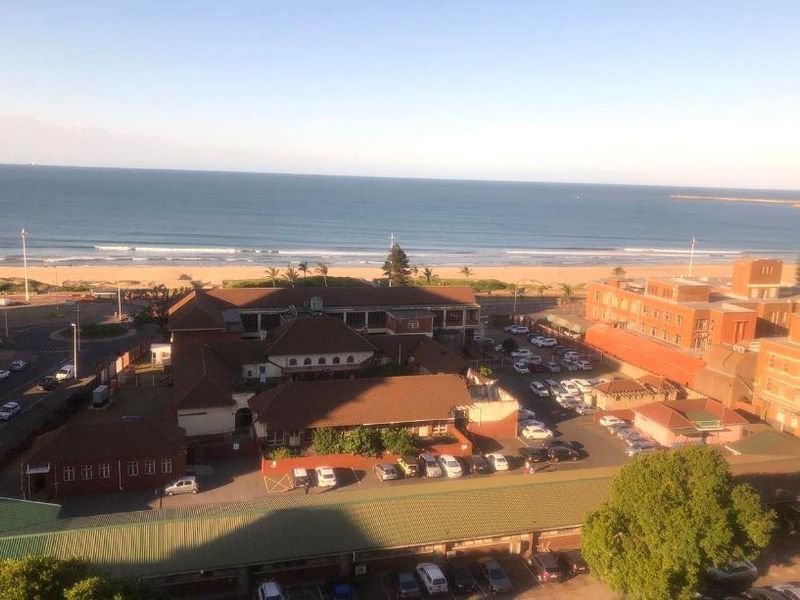 Elevated aerial view overlooking the coastline, beach, and surrounding urban infrastructure.