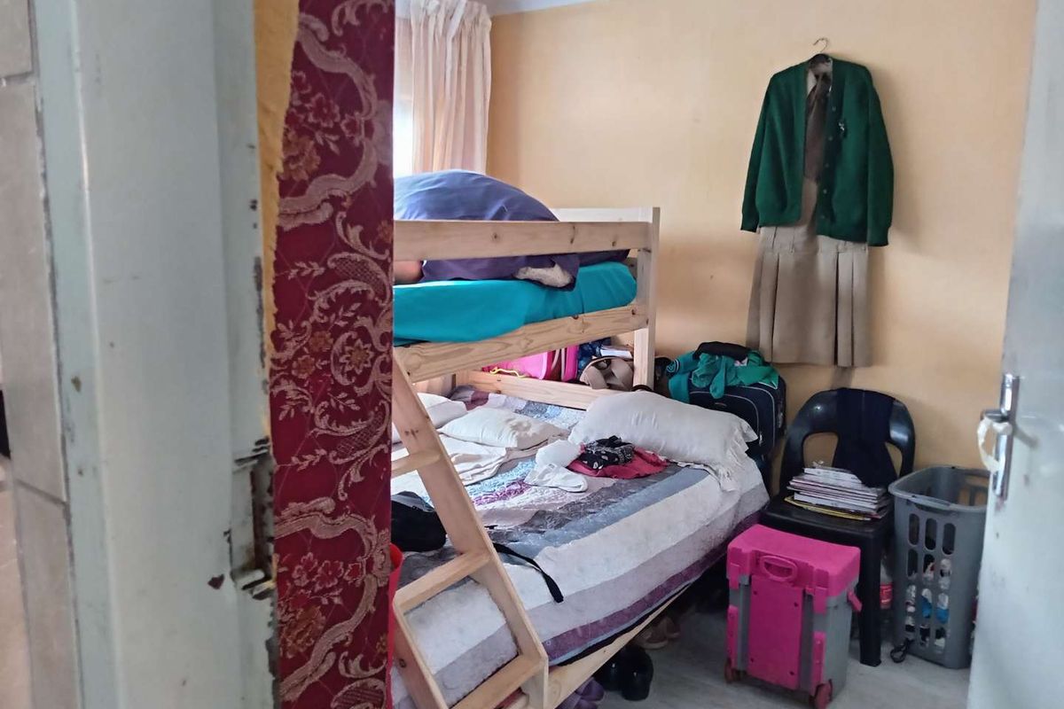 A bedroom space featuring coving, currently showing signs of wear including peeling wallpaper and damage to the door frame.