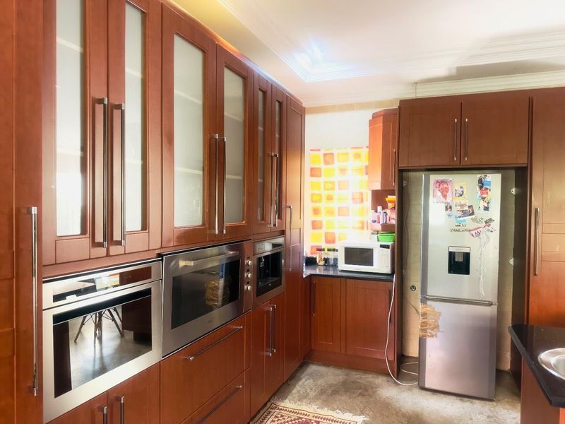 A functional kitchen featuring extensive wooden cabinetry, built-in oven, microwave, and integrated appliances with dark stone countertops.