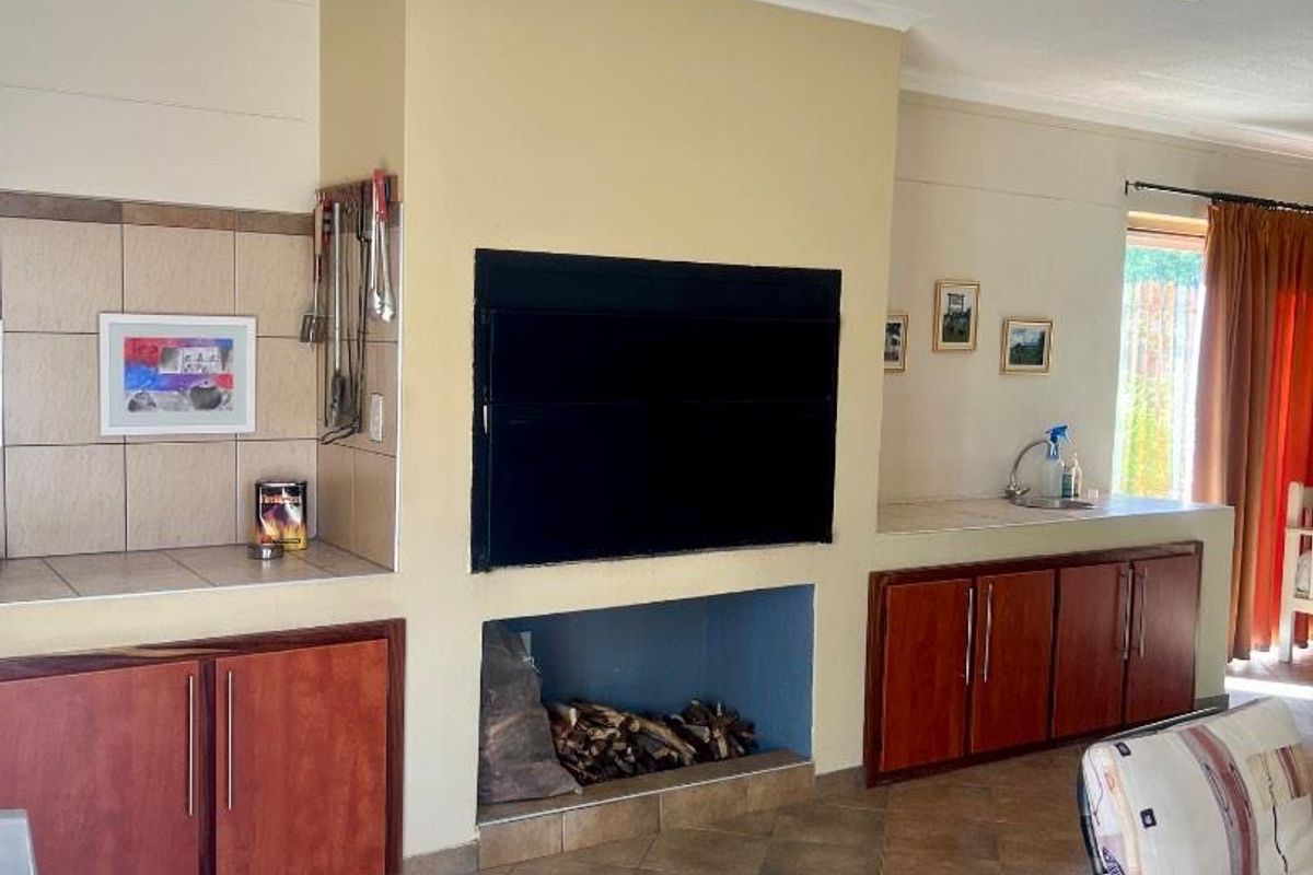 Indoor entertainment area featuring a built-in fireplace, tiled prep surfaces, and wooden cabinetry, providing a functional space for gatherings.