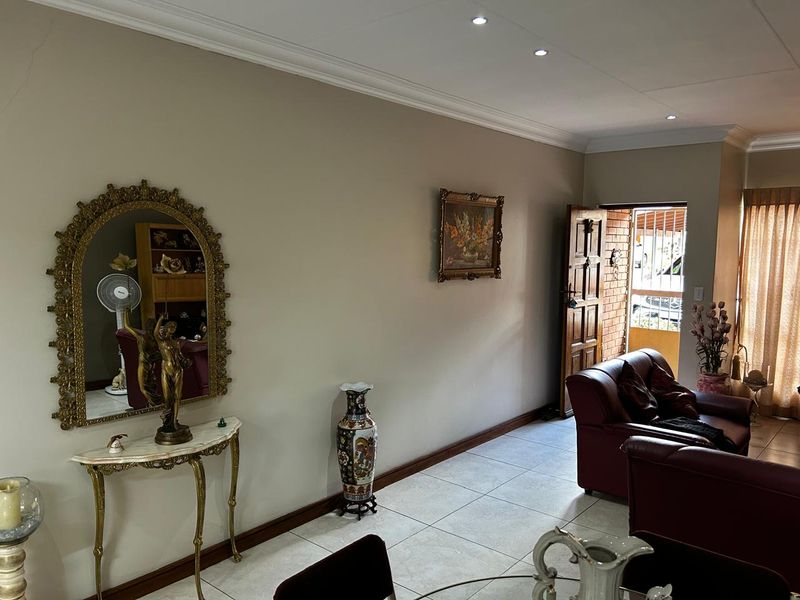 A view of the living area featuring tiled flooring, recessed ceiling lighting, and a solid timber entrance door with security gate.