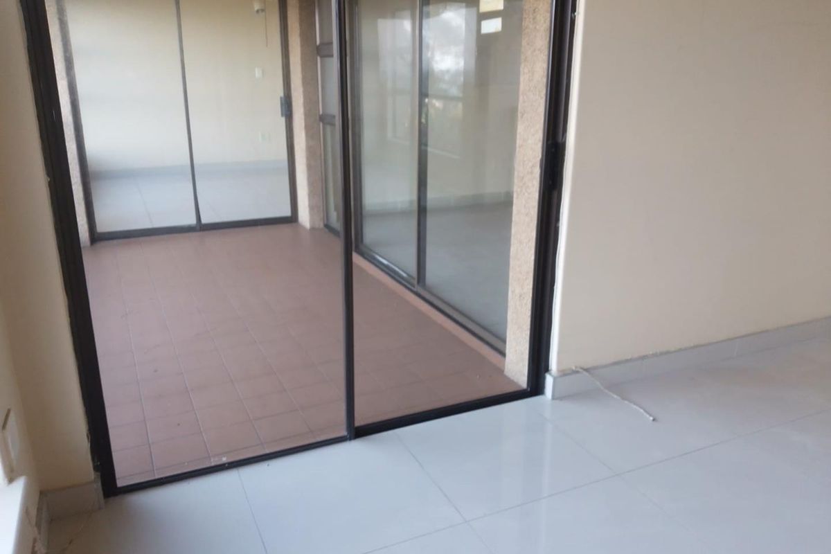An empty interior space featuring large sliding glass doors that open onto a tiled patio area, providing a seamless transition between indoor and outdoor living.