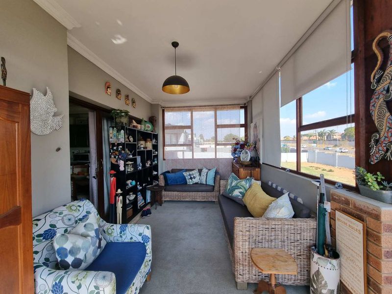 A bright, enclosed patio or sunroom featuring large windows with roller blinds, a pendant light, and direct access to the interior living space.