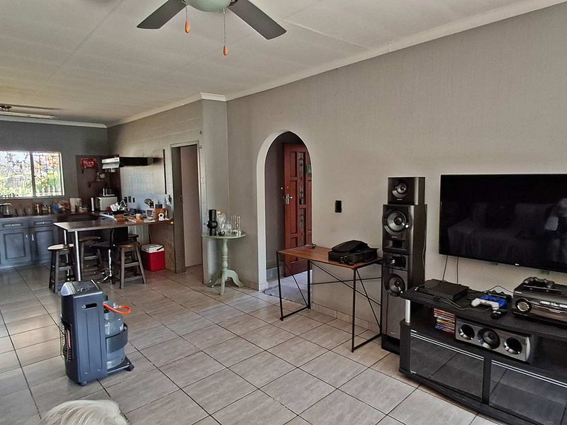 Open plan living area featuring tiled flooring, a ceiling fan, and an integrated kitchen with cabinetry and a breakfast island.