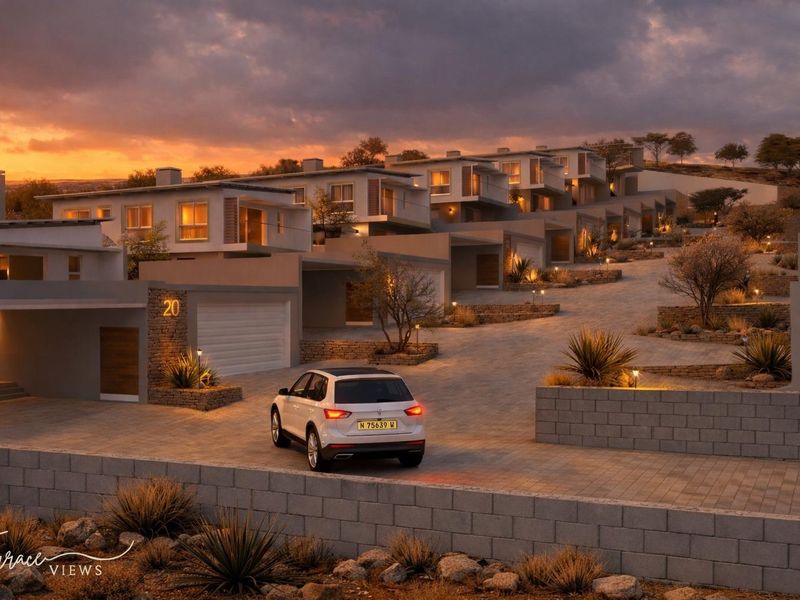 A modern townhouse development featuring tiered architecture, stone accents, paved driveways, and integrated exterior lighting at dusk.