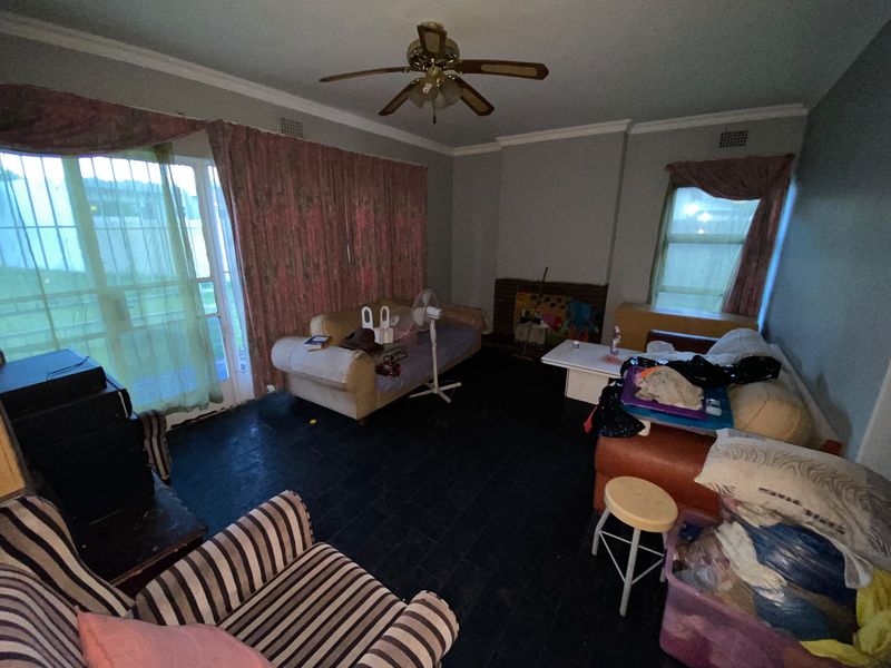 Living room featuring a brick fireplace, ceiling fan, and sliding glass door access to the exterior.
