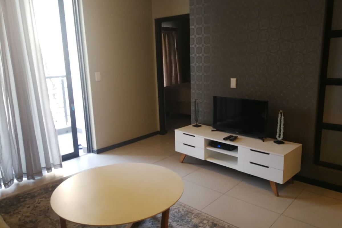 A living room featuring tiled flooring, a textured feature wall, and a sliding glass door providing access to an outdoor area.