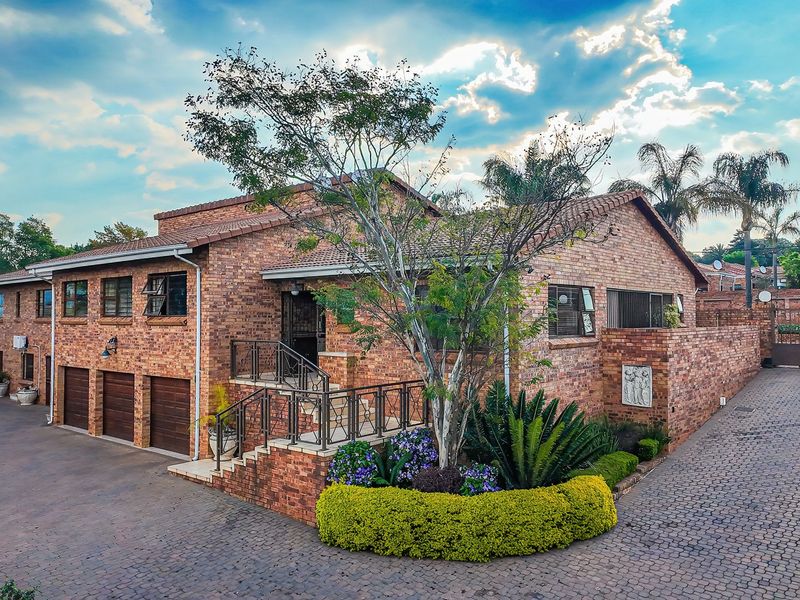 A well-maintained face-brick house featuring a triple garage, paved driveway, and established garden with secure gated access.