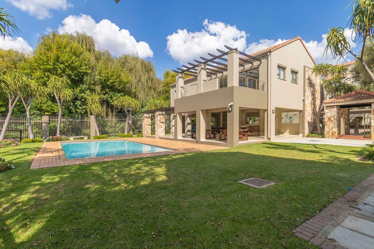 A spacious rear exterior view featuring a swimming pool, manicured lawn, and a covered patio area with a pergola.