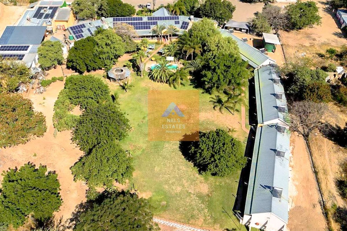 Aerial view of a hotel property featuring extensive landscaped grounds, a swimming pool, and multiple buildings equipped with solar panel installations.