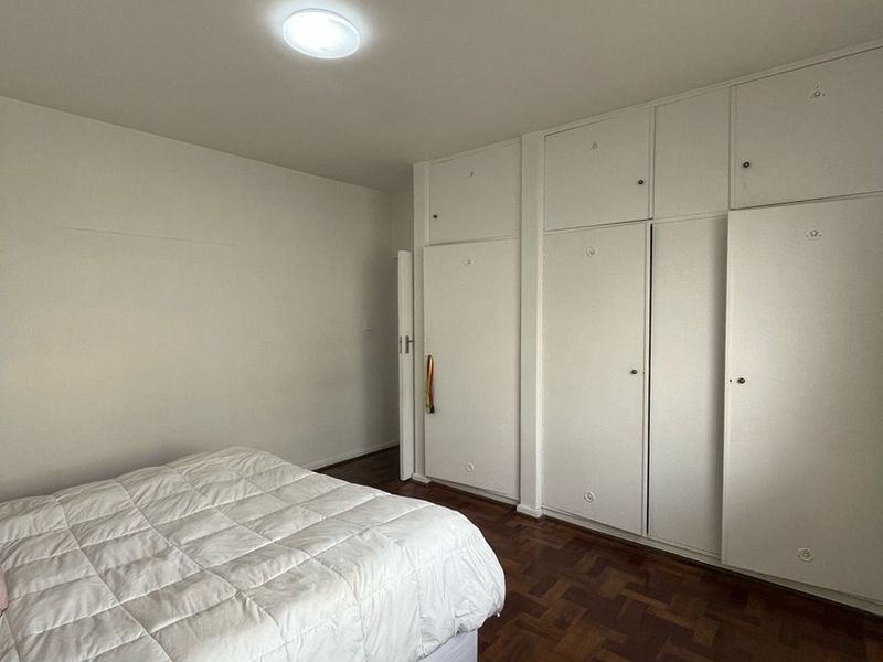 A bedroom featuring classic parquet flooring and extensive floor-to-ceiling built-in cupboards providing ample storage space.