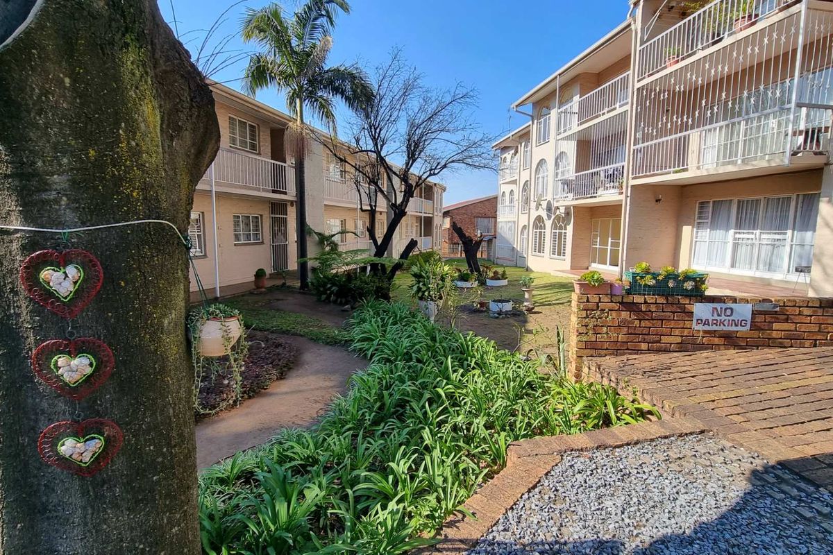 A view of the apartment complex rear courtyard featuring landscaped gardens, paved walkways, and multi-level balconies.