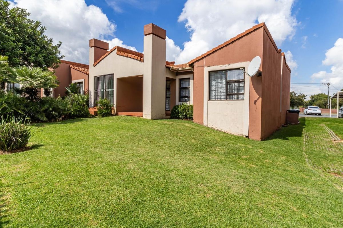 Rear view of the townhouse featuring a private garden, covered patio area, and traditional terracotta roof tiles.