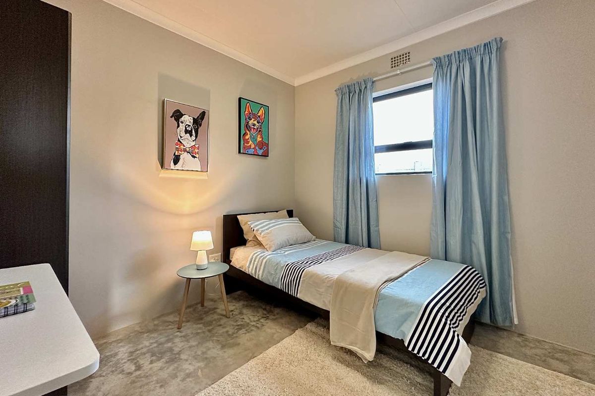 A well-maintained bedroom featuring neutral wall tones, a built-in wardrobe, and a functional ventilation grille, offering a clean and comfortable living space.