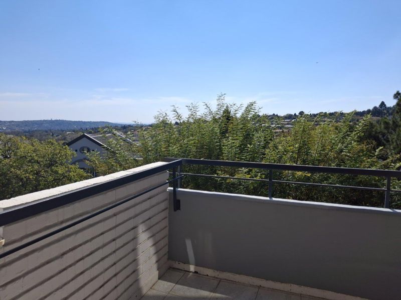 A private balcony featuring tiled flooring, a brick wall, and a metal railing, offering elevated views of the surrounding neighborhood.
