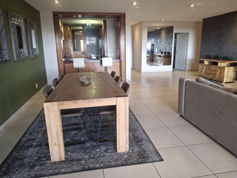 Spacious open-plan living and dining area featuring tiled floors, recessed lighting, and a functional kitchen with a breakfast bar.