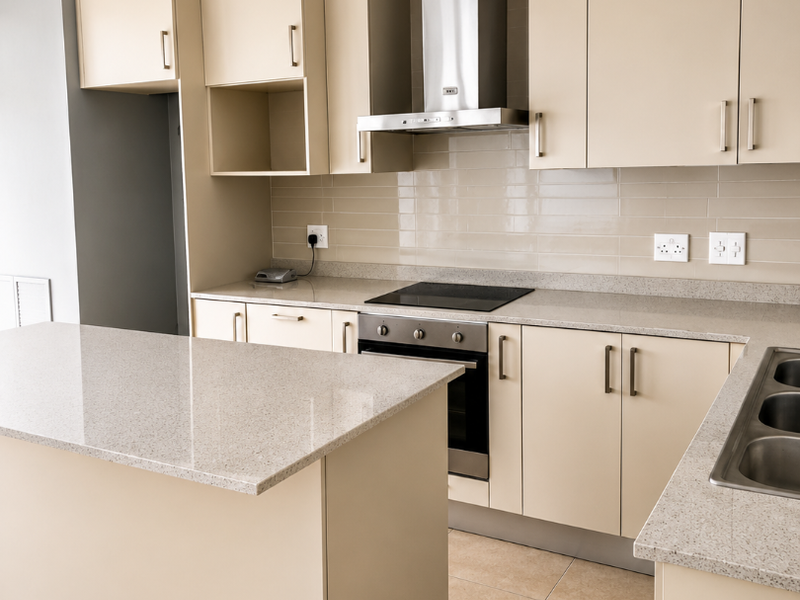 Modern kitchen featuring neutral cabinetry, stone countertops, integrated oven and hob, stainless steel extractor fan, and tiled flooring in a clean, open layout.