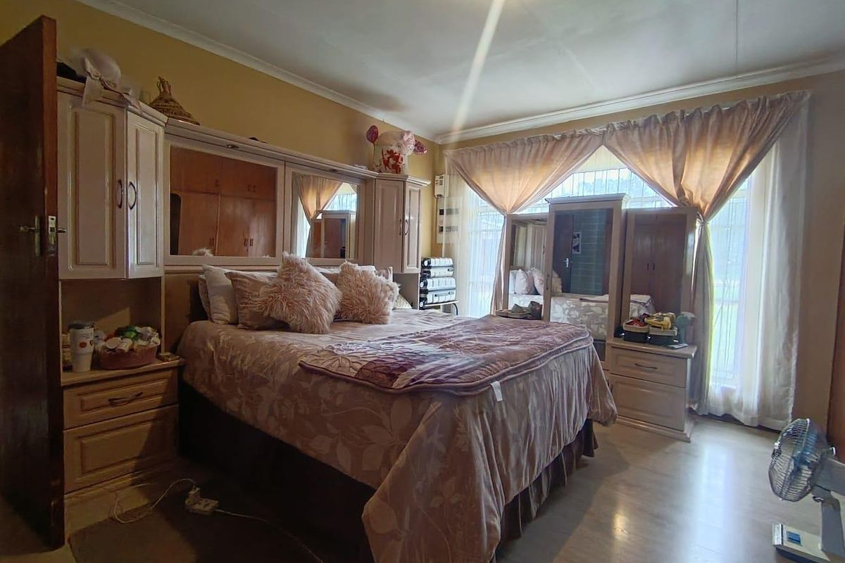 A bedroom featuring built-in cabinetry and large windows with curtain treatments, providing natural light and storage space.
