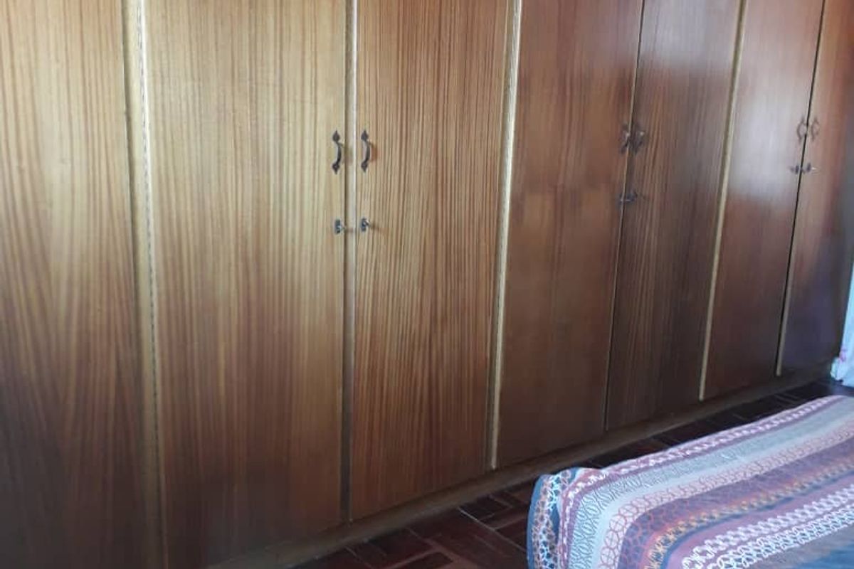 Bedroom featuring extensive floor-to-ceiling built-in wooden cabinetry and traditional parquet flooring.