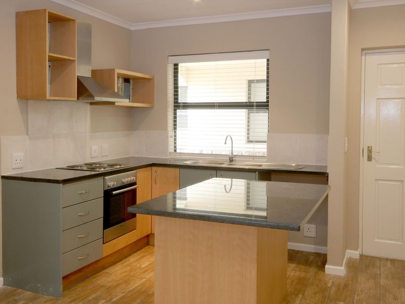 A clean and functional kitchen featuring modern cabinetry, granite countertops, a built-in oven and hob, and a convenient central island.