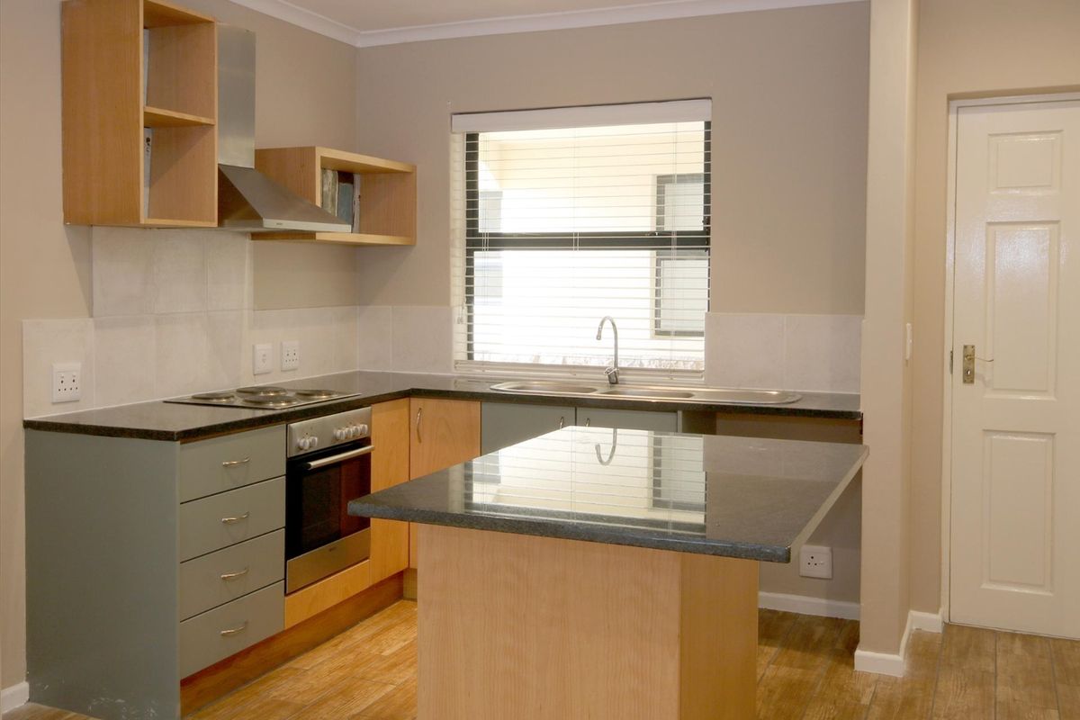 A clean and functional kitchen featuring modern cabinetry, granite countertops, a built-in oven and hob, and a convenient central island.