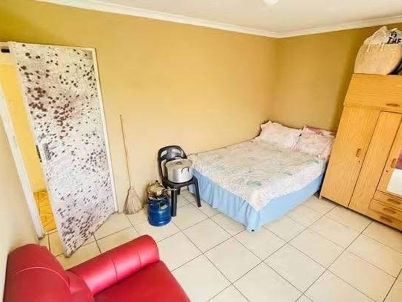 A bedroom featuring tiled flooring and coved ceilings, requiring cosmetic updates to the wall finishes and door surfaces.