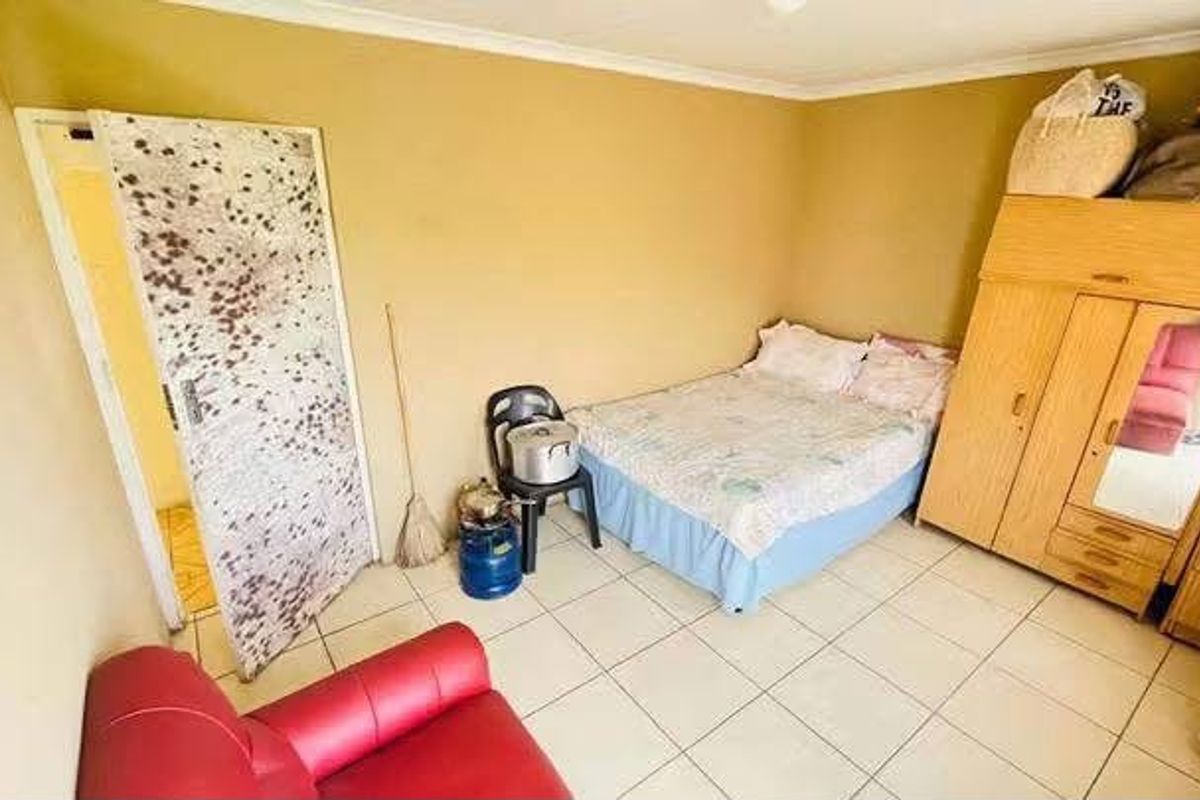 A bedroom featuring tiled flooring and coved ceilings, requiring cosmetic updates to the wall finishes and door surfaces.