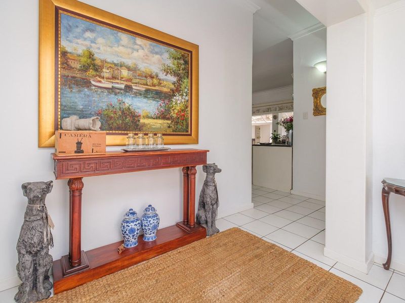A bright entrance hall featuring neutral tiled flooring and an open archway leading into the main living areas of the home.