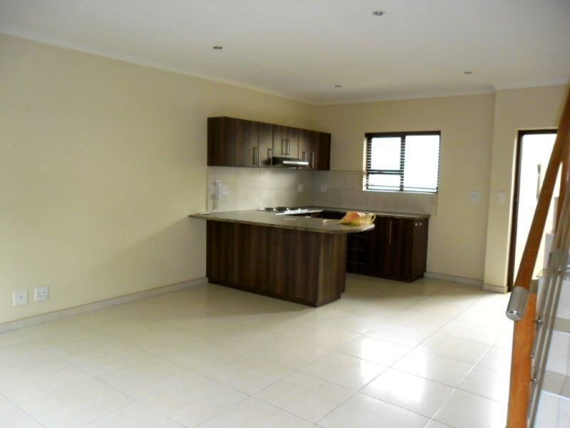 Spacious open-plan living area featuring a modern kitchen with built-in cabinetry, stone countertops, and tiled flooring throughout.