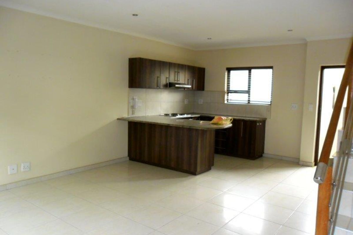 Spacious open-plan living area featuring a modern kitchen with built-in cabinetry, stone countertops, and tiled flooring throughout.