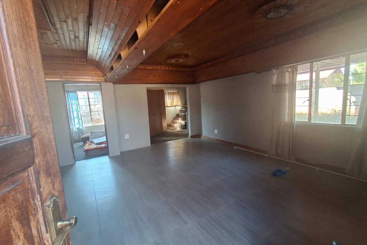 Spacious living area featuring a distinctive timber-clad vaulted ceiling and modern tiled flooring, currently vacant and awaiting finishing touches.
