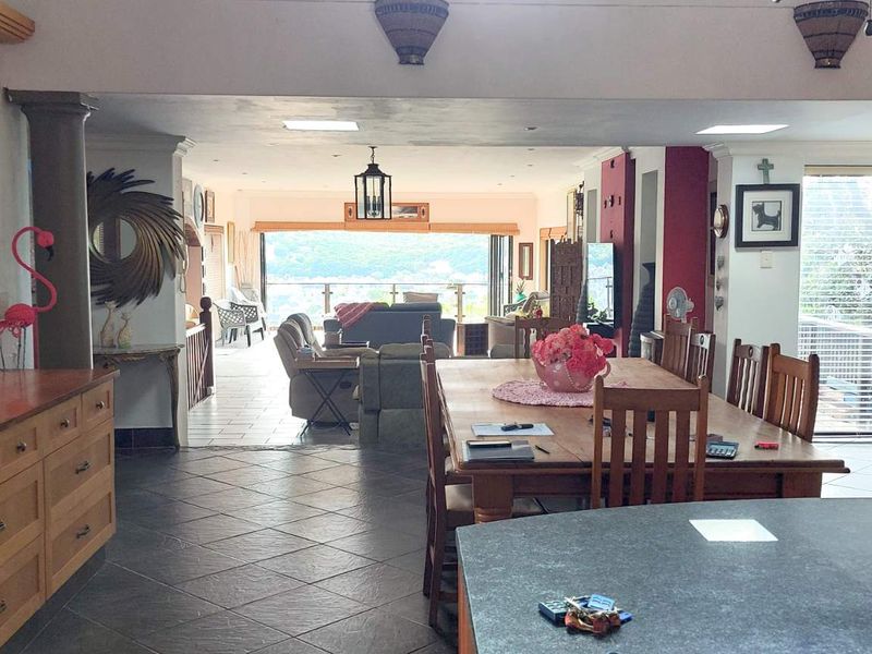 Spacious open-plan living and dining area featuring tiled floors, built-in cabinetry, and large sliding doors that open to a scenic outdoor view.