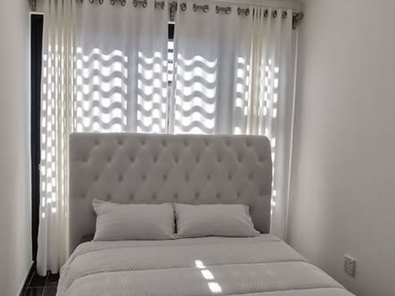 A well-lit bedroom featuring modern recessed downlights, a decorative crystal chandelier, and floor-to-ceiling curtain tracks.