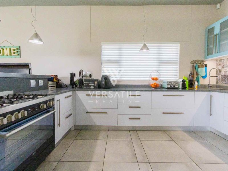 A functional kitchen featuring white cabinetry, a gas stove with oven, tiled flooring, and a tiled backsplash, offering a clean and practical workspace.