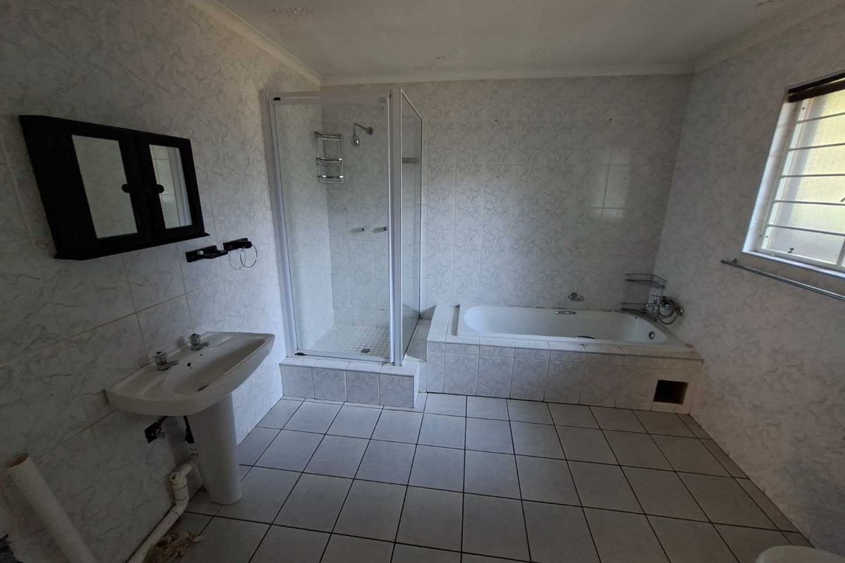 A spacious bathroom featuring a pedestal basin, a separate shower enclosure, and a built-in bathtub with tiled finishes throughout.