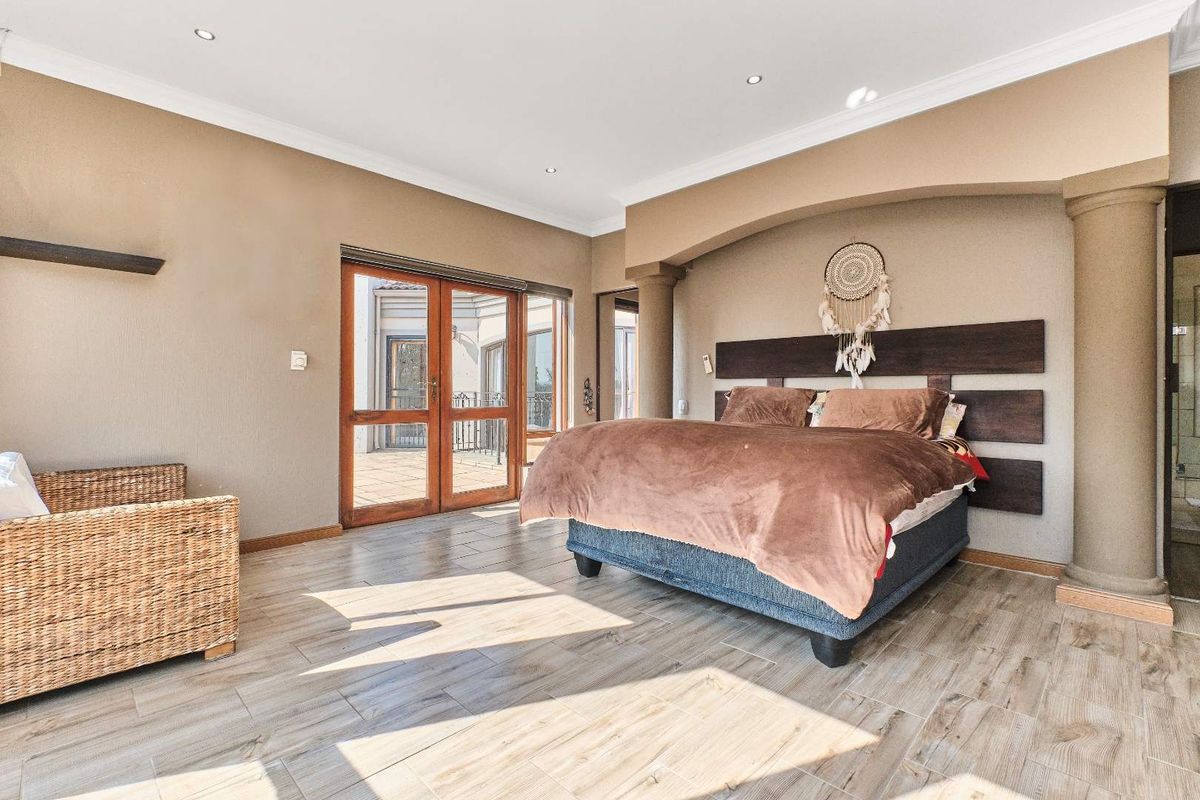 Spacious bedroom featuring wood-look tile flooring, recessed ceiling lighting, and double glass doors providing direct access to an outdoor patio area.