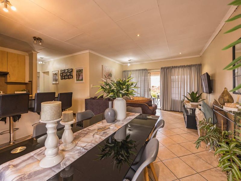 Open-plan living and dining area featuring tiled flooring, a breakfast bar, and sliding glass doors leading to an outdoor space.