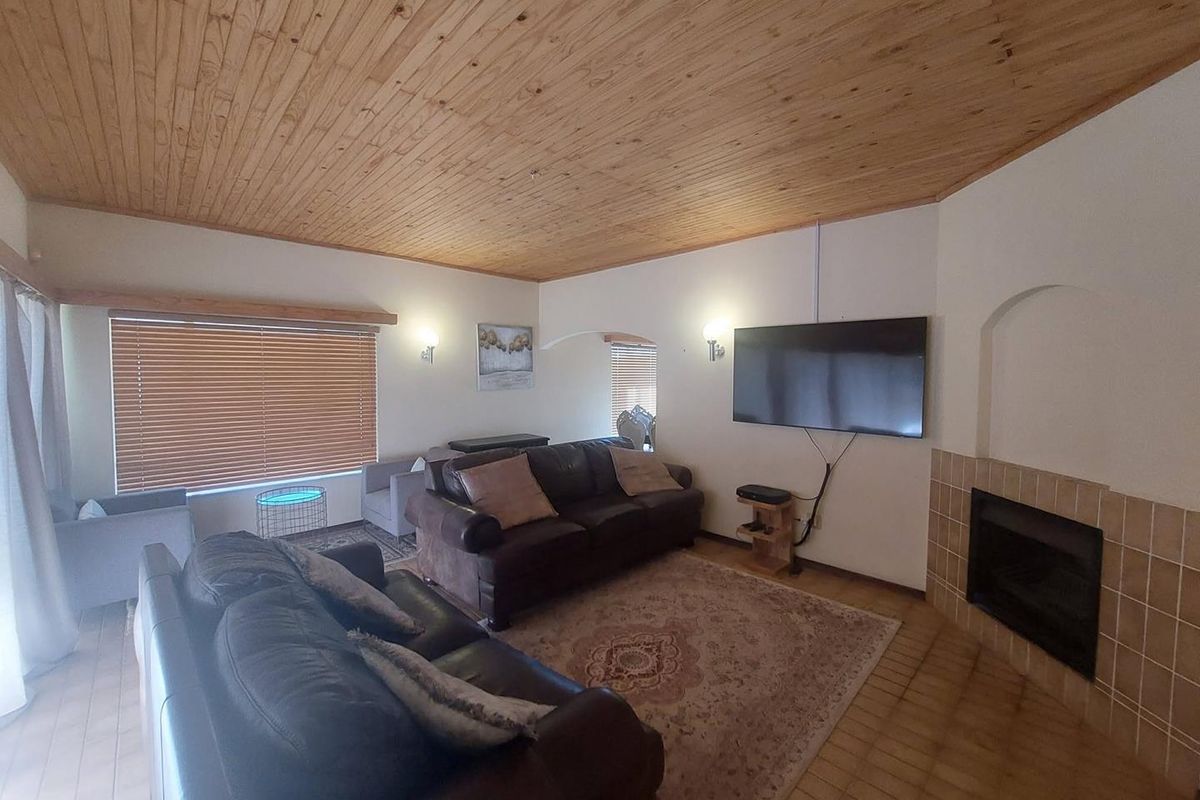 A living room featuring a wood-paneled ceiling, tiled flooring, and a built-in fireplace with tiled surround.