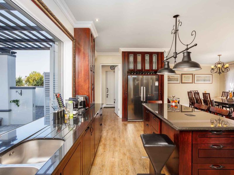 Spacious open-plan kitchen featuring dark wood cabinetry, granite countertops, a central island, and seamless flow to the outdoor patio area.