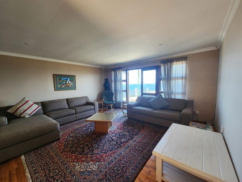 Spacious living room featuring hardwood flooring, crown molding, and a sliding glass door providing natural light and ocean views.
