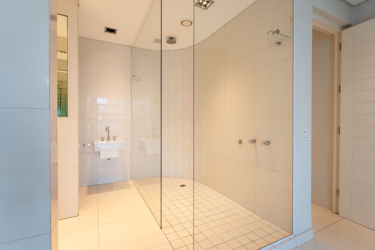 Modern bathroom featuring a spacious walk-in shower with glass enclosure, wall-mounted basin, and clean, neutral tiling throughout.
