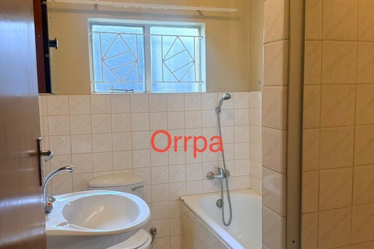 A functional bathroom featuring a bathtub with shower attachment, pedestal basin, and tiled flooring, providing a practical layout for daily use.