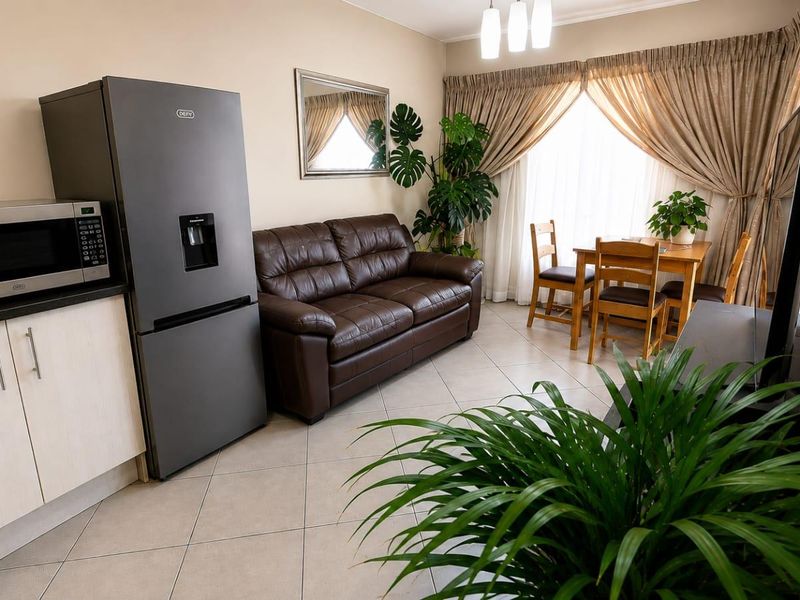 Open-plan living and kitchen area featuring tiled flooring, neutral walls, and built-in cabinetry, creating a functional and cohesive living space.