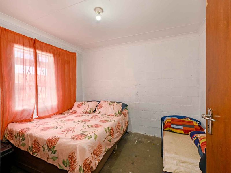 A bedroom featuring exposed blockwork walls and concrete flooring, offering a blank canvas for renovation and interior finishing.