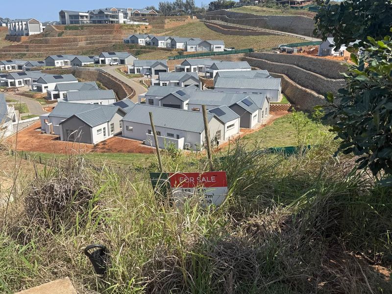 An elevated view of a residential estate development featuring multiple modern homes, paved roads, and terraced retaining walls.