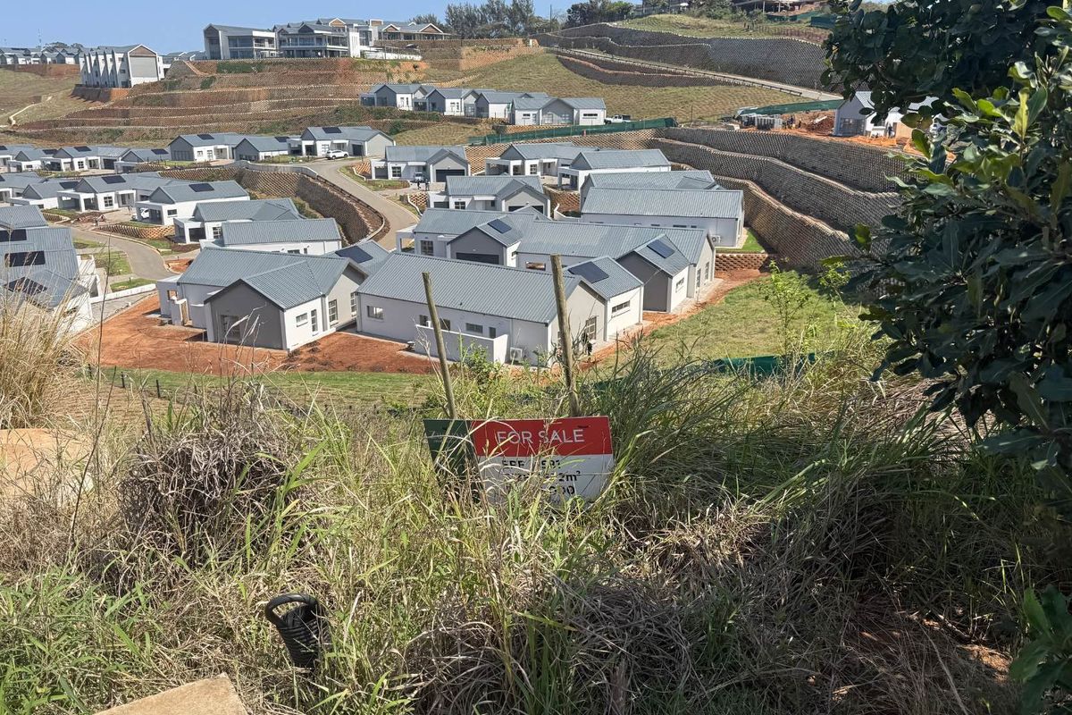 An elevated view of a residential estate development featuring multiple modern homes, paved roads, and terraced retaining walls.