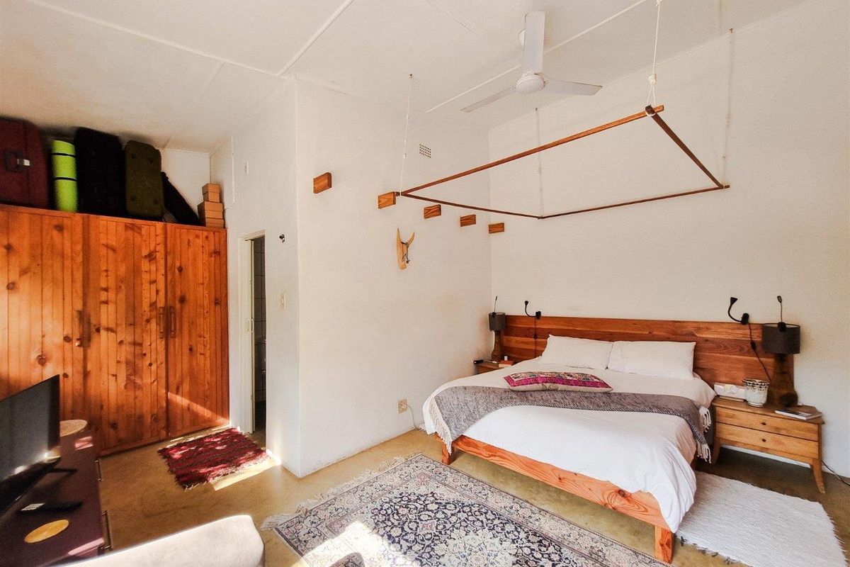 A bedroom featuring a built-in wooden wardrobe, ceiling fan, and a wooden headboard integrated into the wall design.