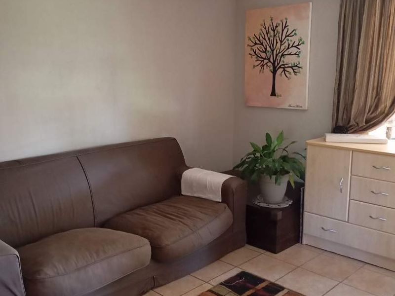 A living room area featuring neutral wall paint and tiled flooring, providing a functional and well-lit space for relaxation.