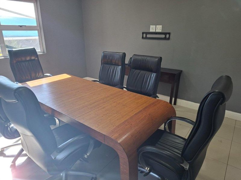 A functional office space featuring tiled flooring, neutral grey walls, and integrated wall-mounted television bracket with power points.
